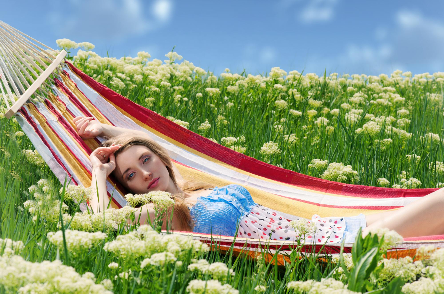 smiling woman sitting hammock among blooming yarrow