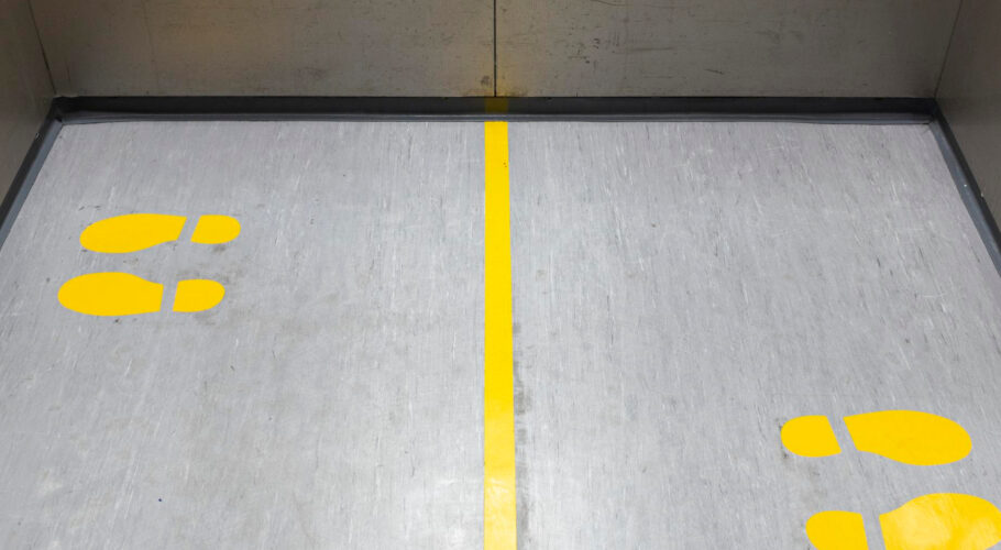 Socially Distancing Covid-19 With Yellow Footprings Inside Public Elevator
