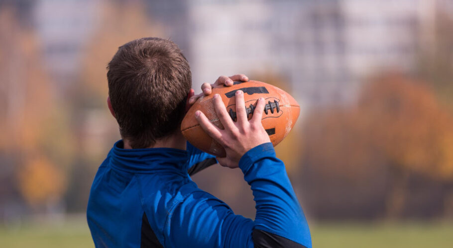 team coach throwing ball into group young gridiron field