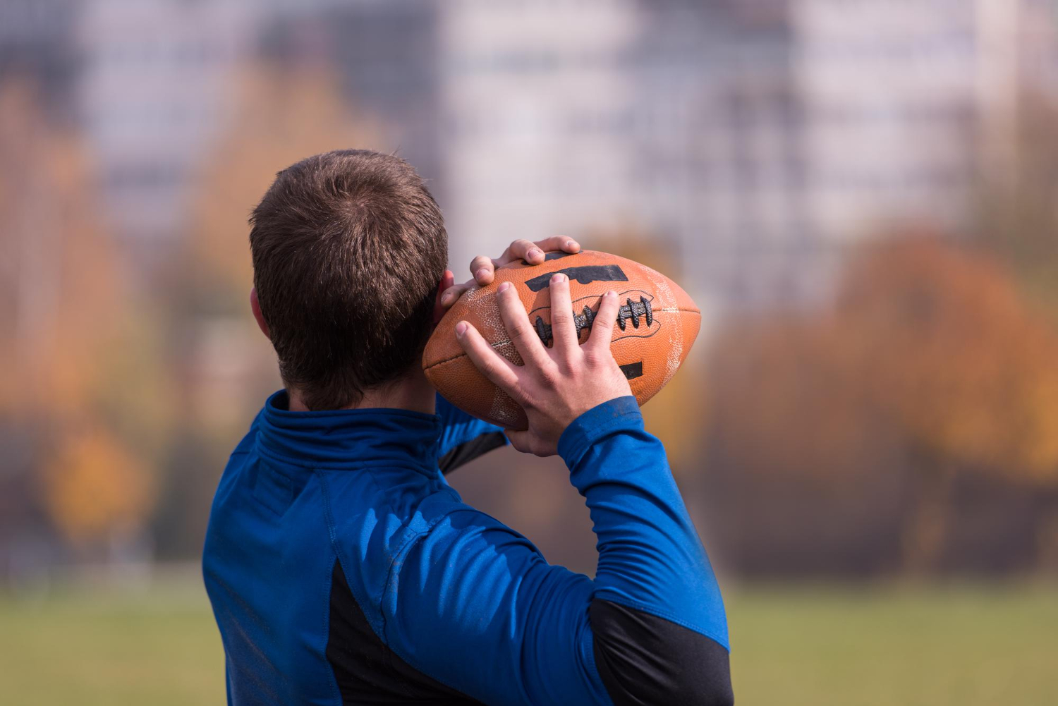 team coach throwing ball into group young gridiron field