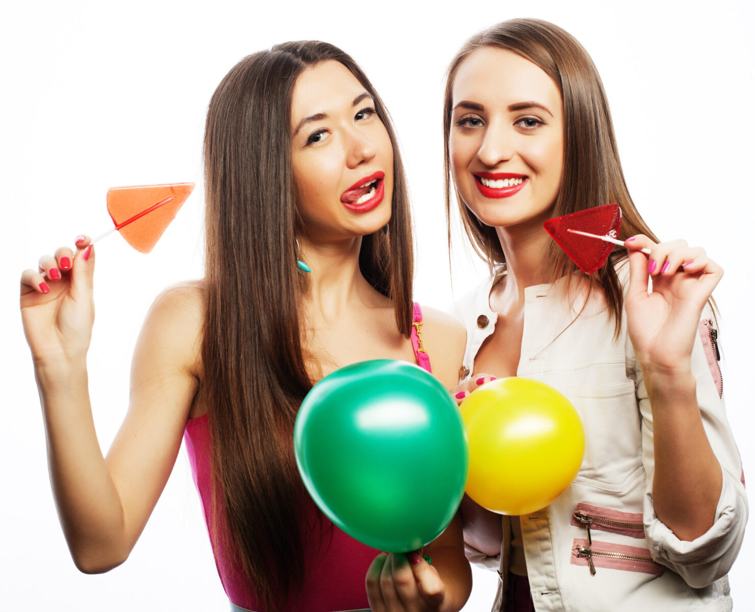 two happy girls smiling holding colored balloons and candy
