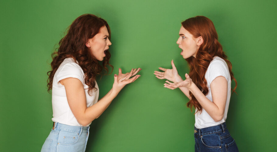 two outraged girls 20s with ginger hair standing face to face crossed shouting at each other