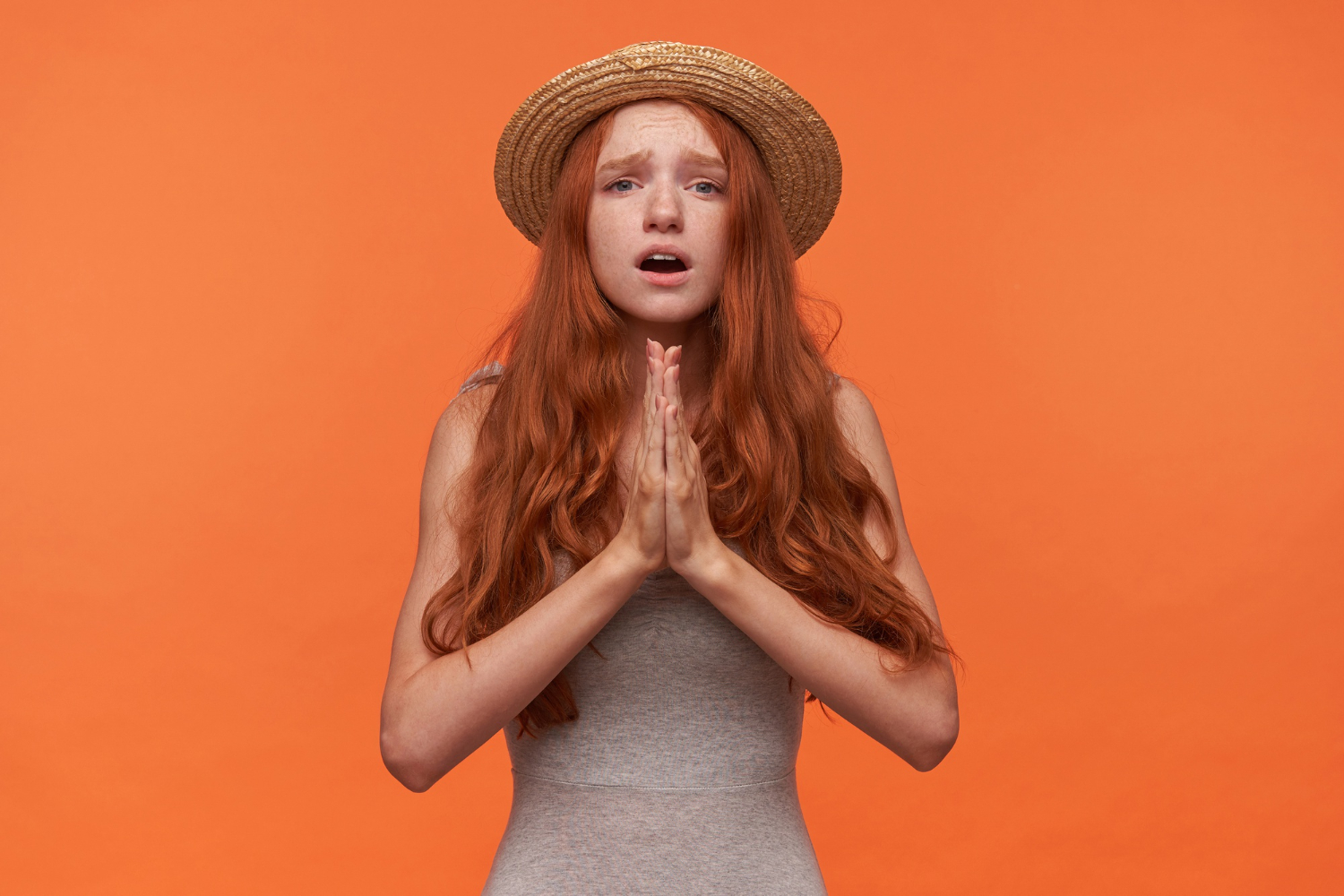 upset young pretty woman with wavy red long hair standing orange