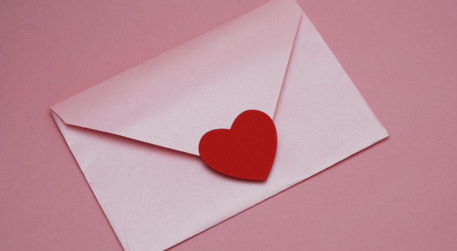 valentines mother woman day background with pink envelope with red paper heart pink background