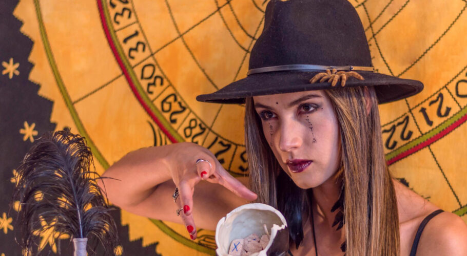 woman esoteric oracle with black hat runic letters writing on her face having seance