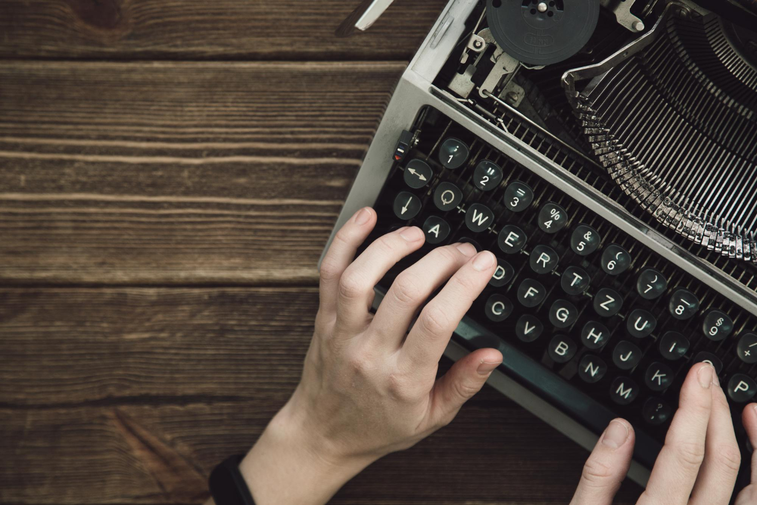 writer types on old typewriter on a wooden table