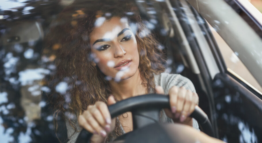 Young arabic woman inside a white car looking through the window