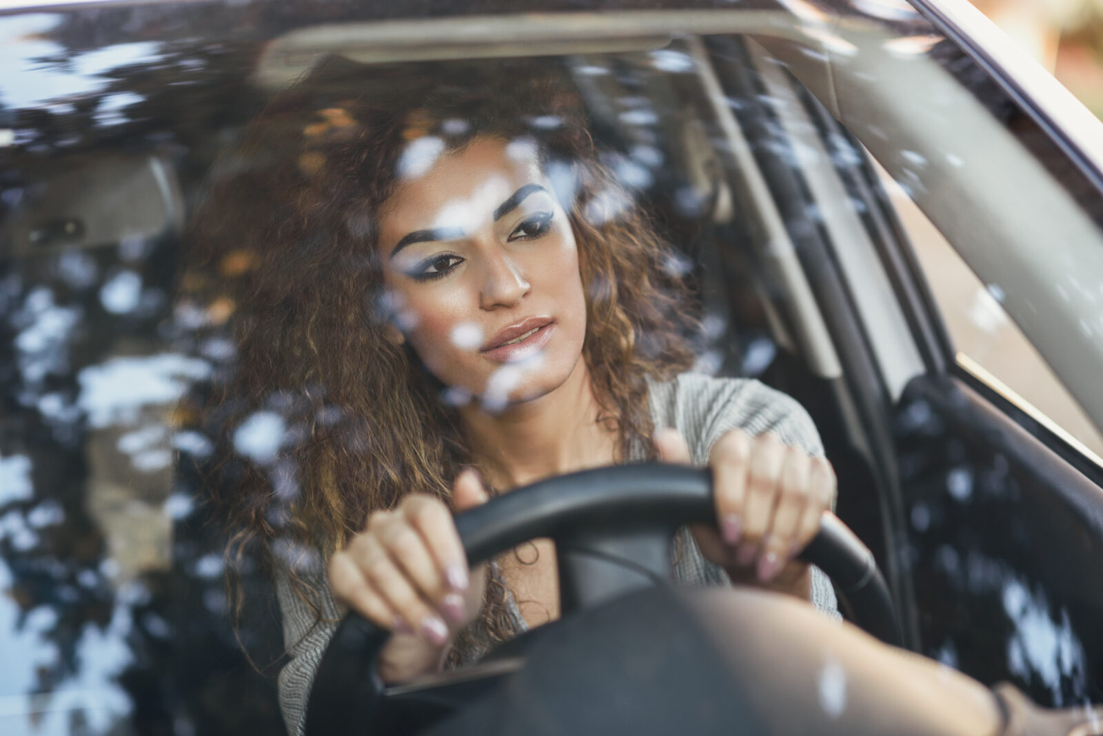 Young arabic woman inside a white car looking through the window