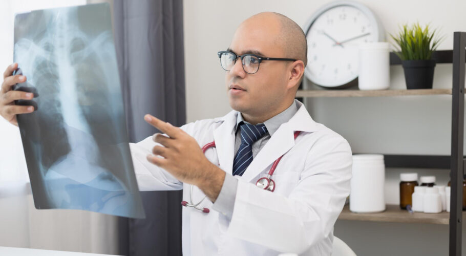 young asian doctor looking xray film patients symptoms from xray results are reported