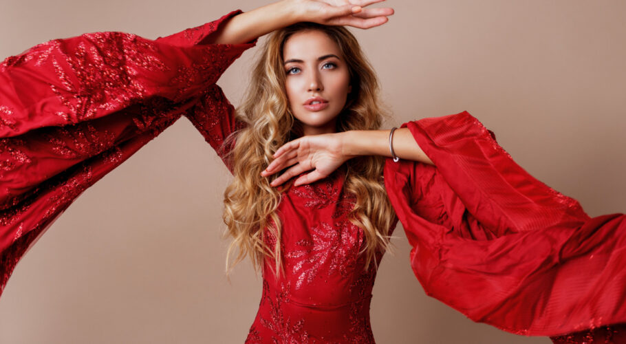 young blond lovely woman luxurious red dress with wide sleeves expressive pose