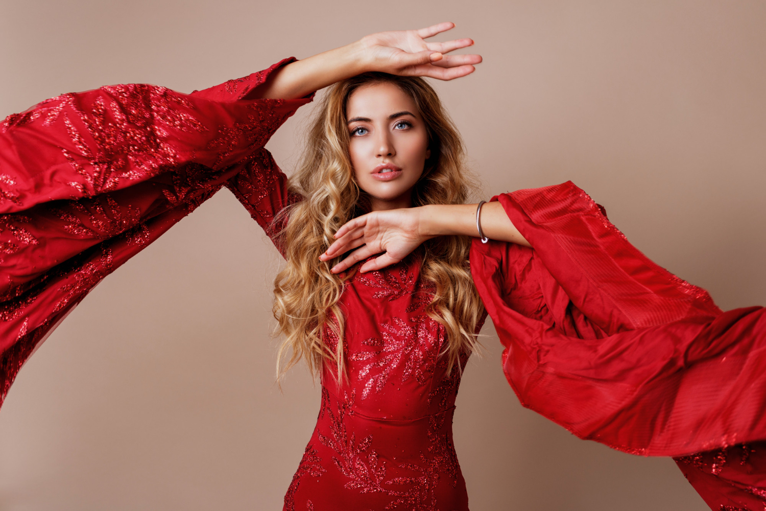 young blond lovely woman luxurious red dress with wide sleeves expressive pose