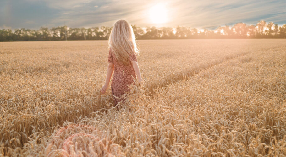 young blonde woman walking field with heat back view