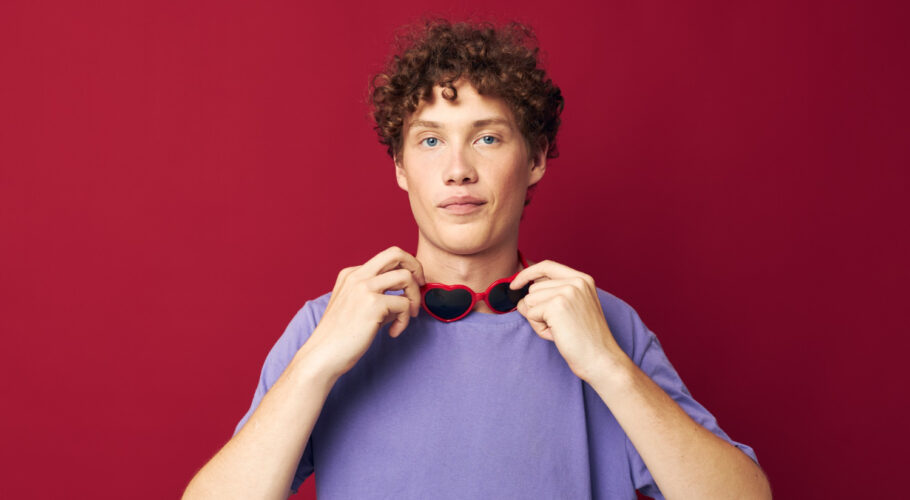 young male teenager with curly hair wearing glasses posing lilac tshirt