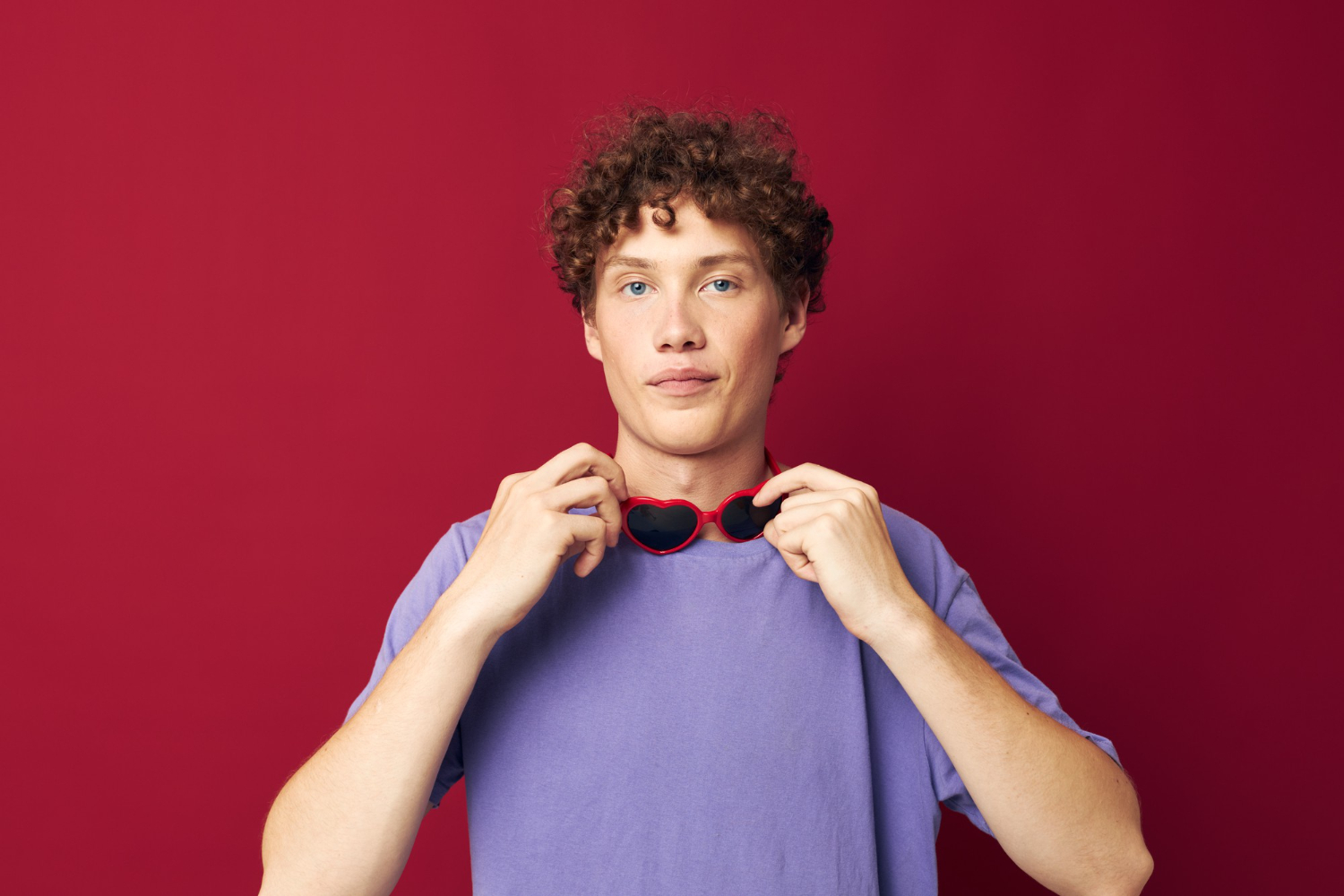 young male teenager with curly hair wearing glasses posing lilac tshirt