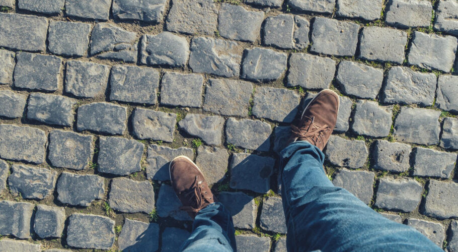 young man stands cobblestones high angle footsie flortrait