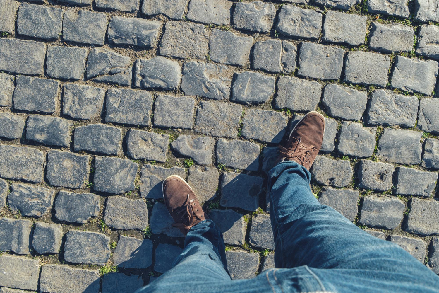 young man stands cobblestones high angle footsie flortrait