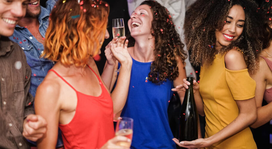 young multiracial friends dancing after party holding alcohol bottles