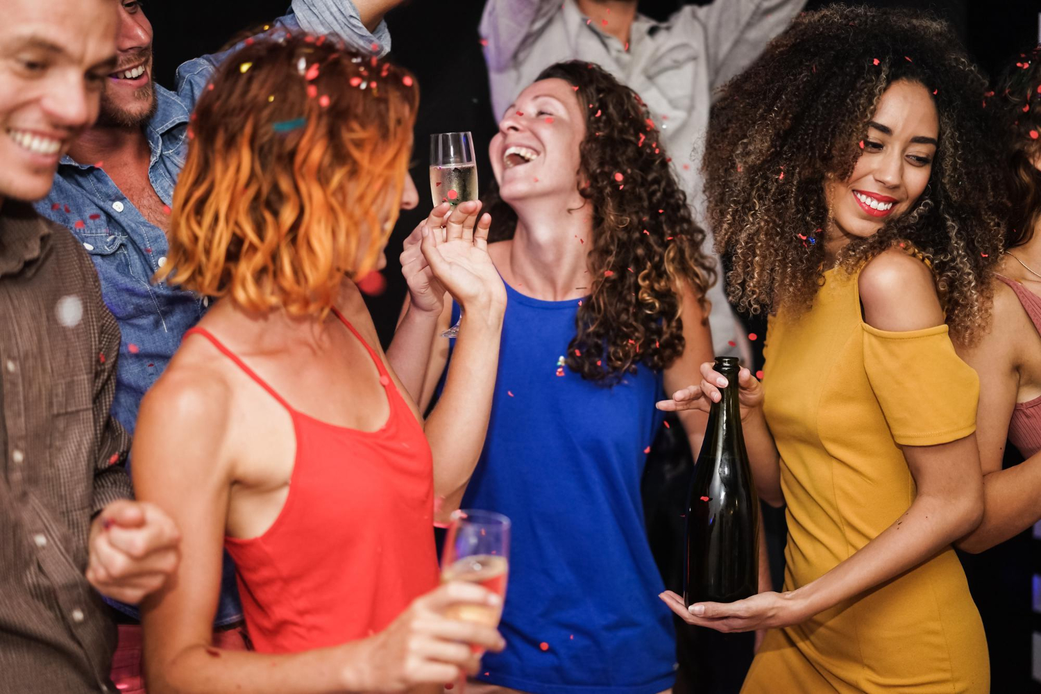 young multiracial friends dancing after party holding alcohol bottles